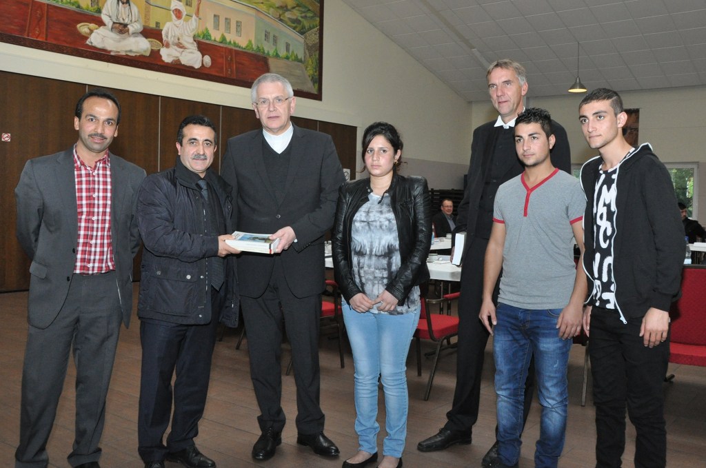 Süleyman Kaya und Sahap Dag dankten Weihbischof Heinrich Timmerevers (von links) und Bischof Jan Janssen für ihren Besuch im Yezidischen Forum Oldenburg. Hanan Ravo Ali, Falah Hasan Khudida und Salah Hasan Khudida schilderten ihre Flucht aus dem Sinjar-Gebirge. Foto: Ludger Heuer